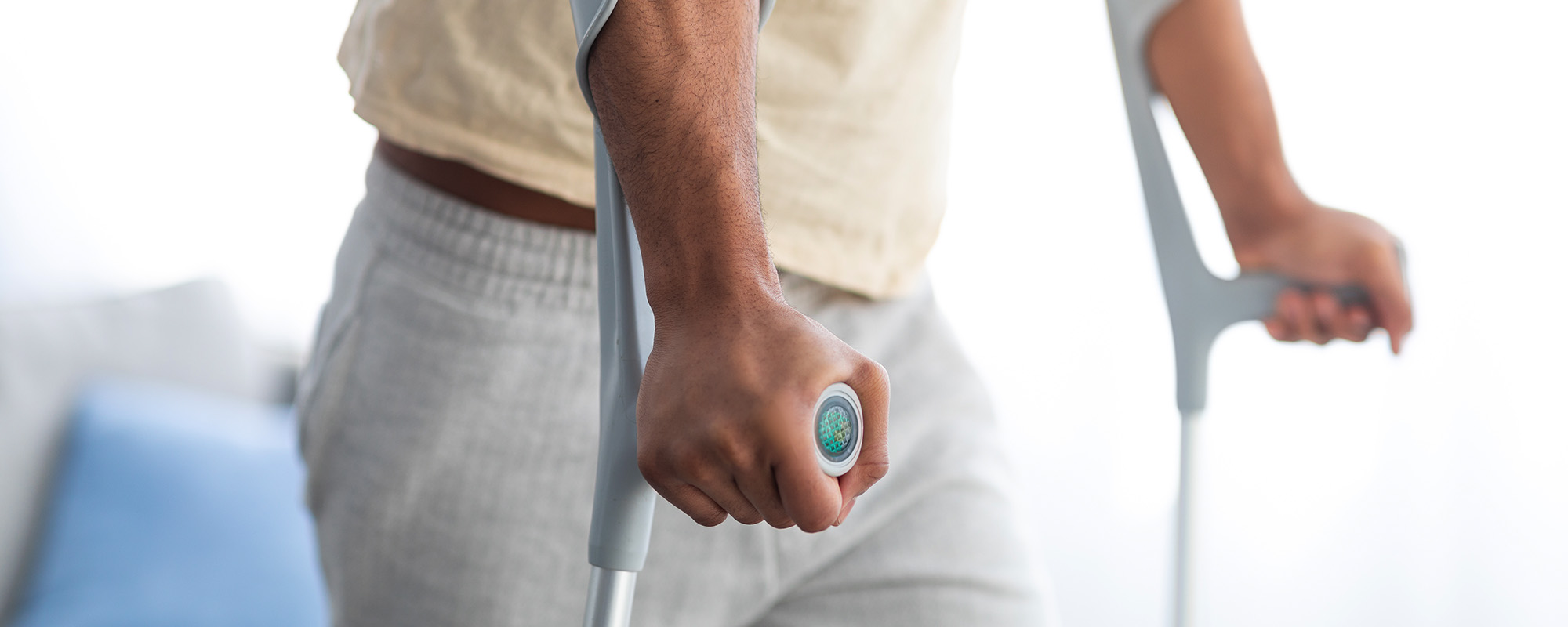Young black man using crutches to walk inside his home - Pikeville Personal Injury Lawyer concept image