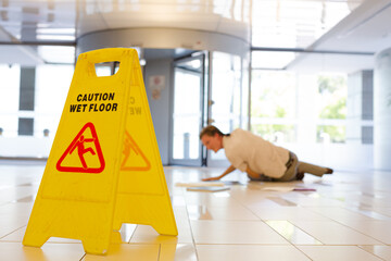 man on ground next to wet floor sign