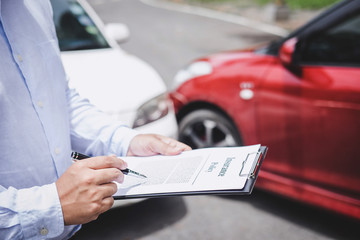 man holding insurance information next to car accident